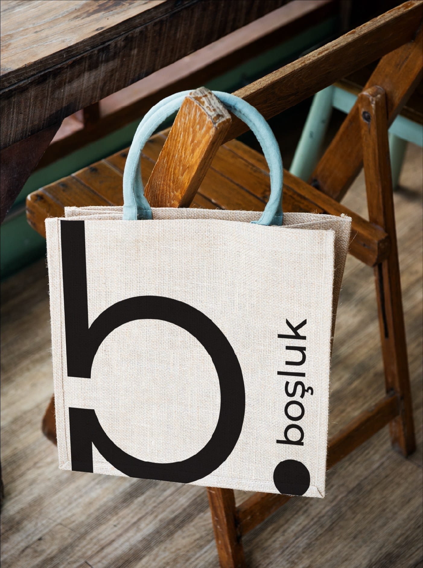 Boşluk-Stofftasche an einem Holzstuhl, großes Logo zentriert auf cremefarbenem Canvas.